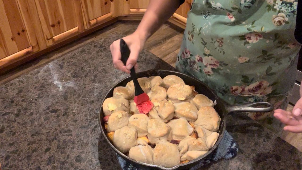 brushing butter on sourdough peach cobbler