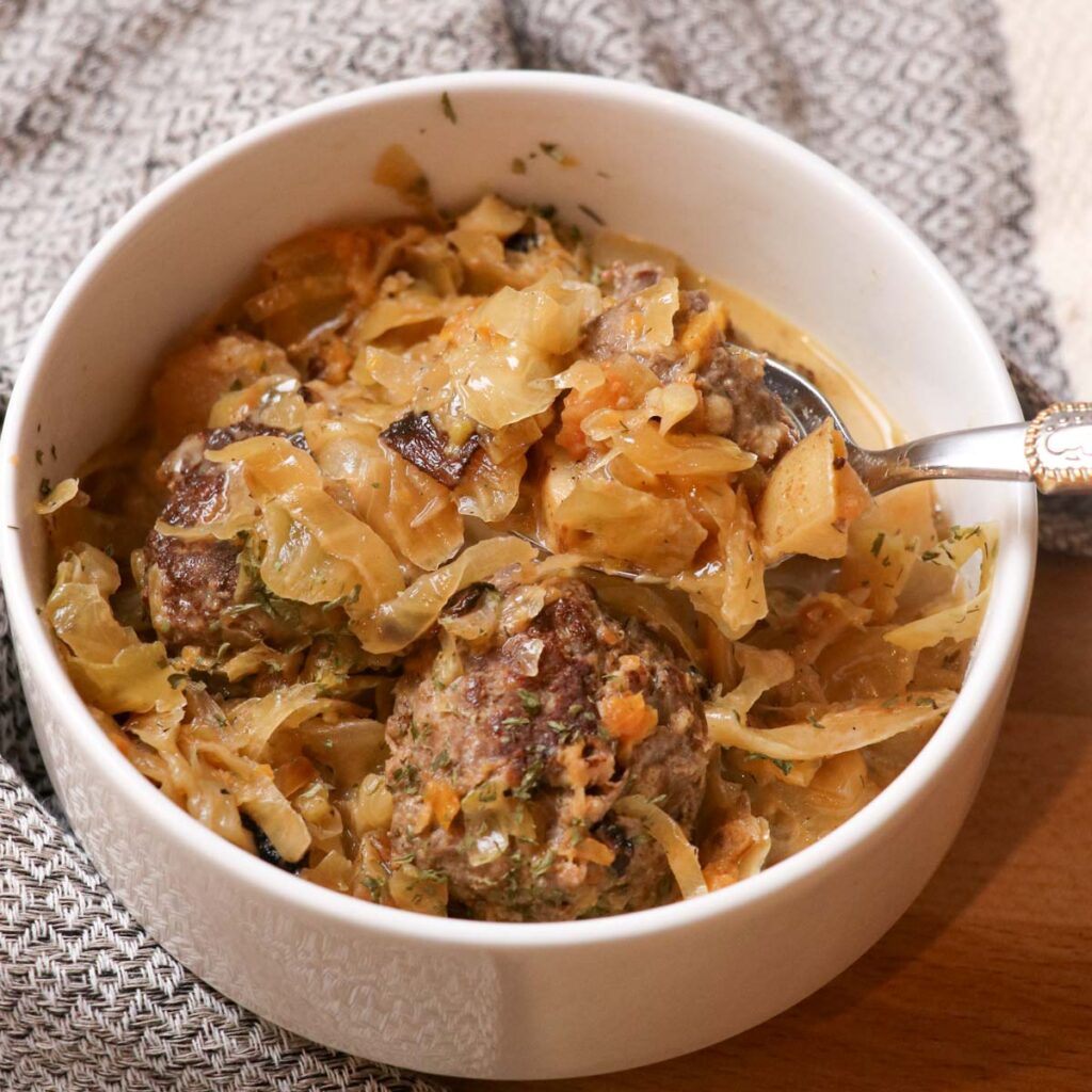 bowl of sauerkraut sausage soup with a spoon