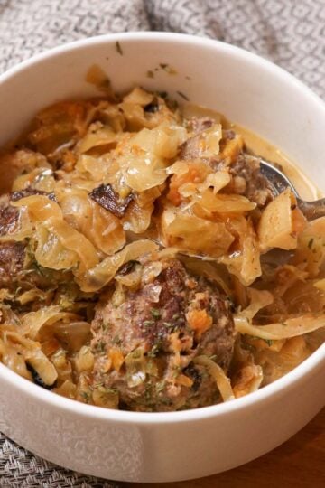 bowl of sauerkraut sausage soup with a spoon
