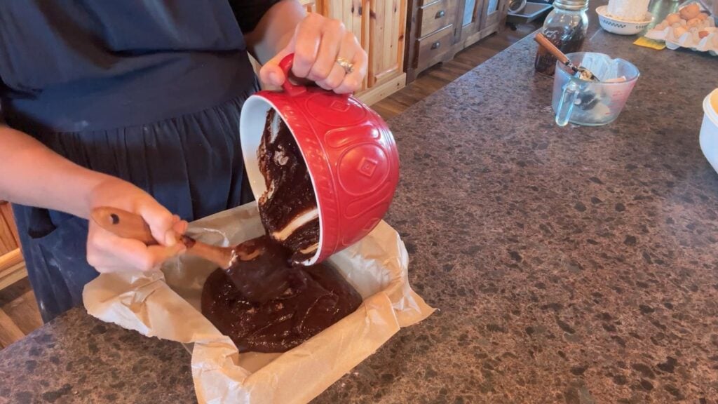 adding brownie batter to pan