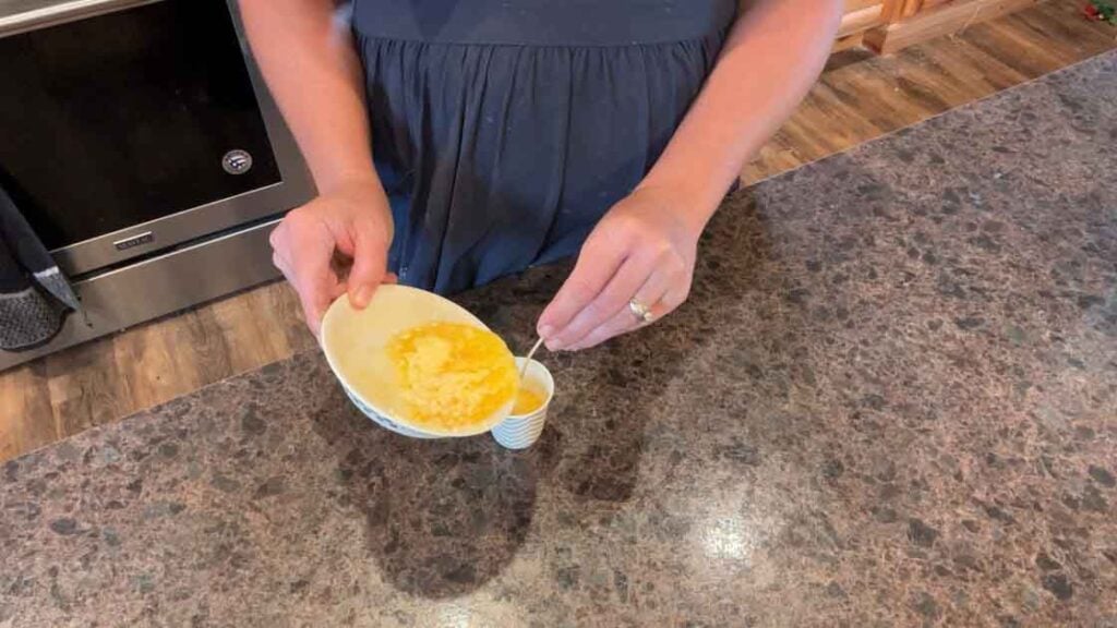 adding butter to paper cup with wick