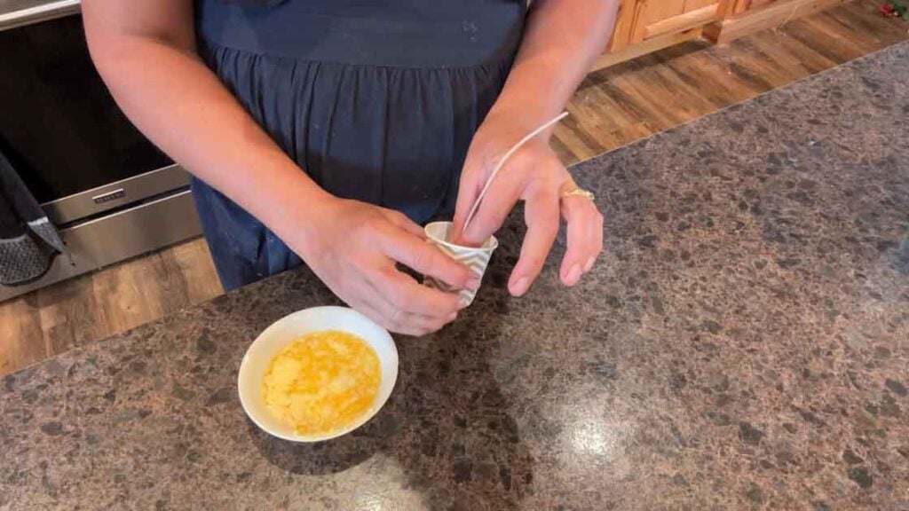 adding wick to paper cup for butter candle
