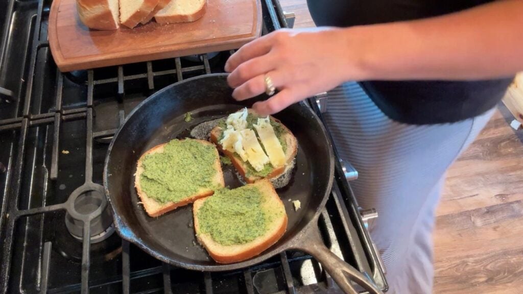 adding homemade mozzarella to pesto grilled cheese sandwich