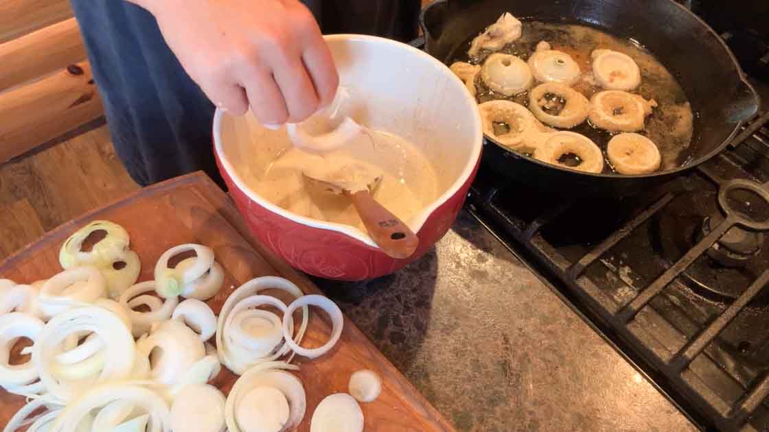 dipping onion rings into sourdough batter