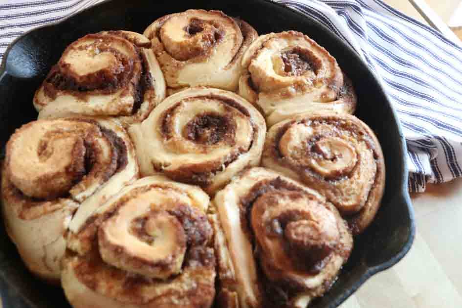 pan of sourdough cinnamon rolls by towel up close