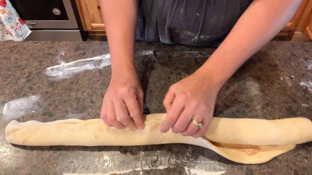 pinching dough log closed on sourdough cinnamon twist