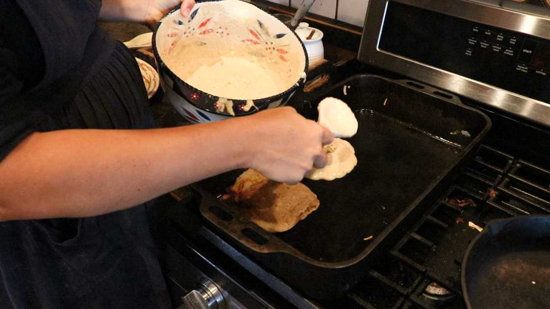 pouring pumpkin pancakes onto a cast iron skillet