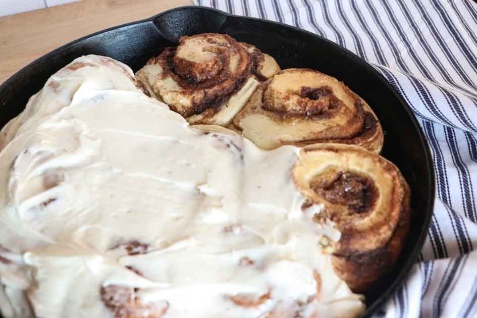sourdough cinnamon rolls half frosted up close