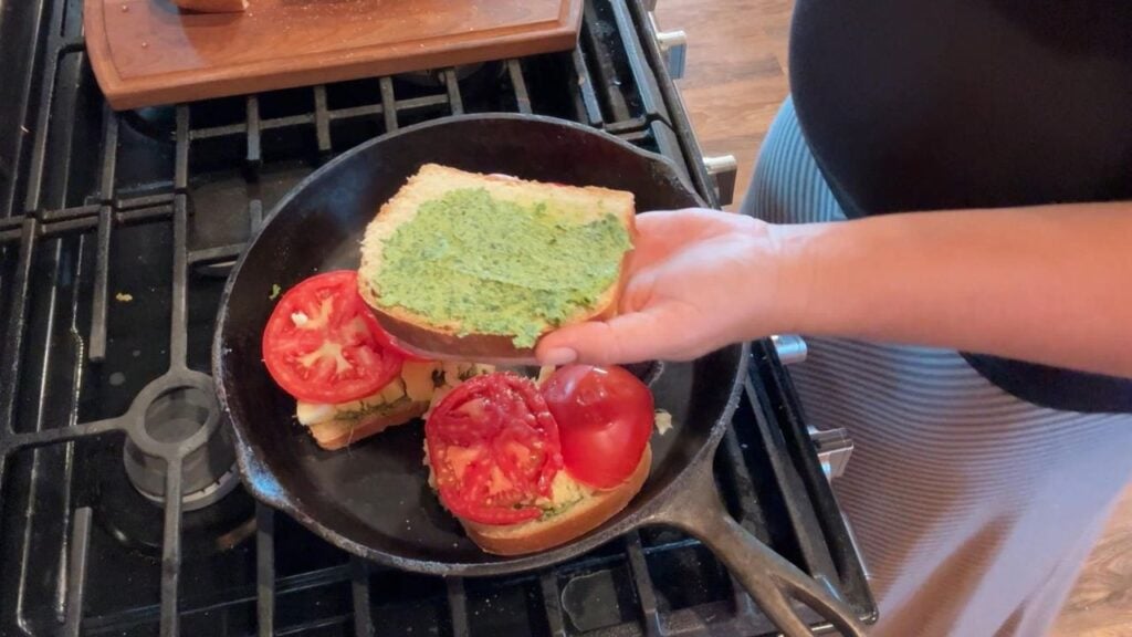 spreading pesto on top of pesto grilled cheese sandwich