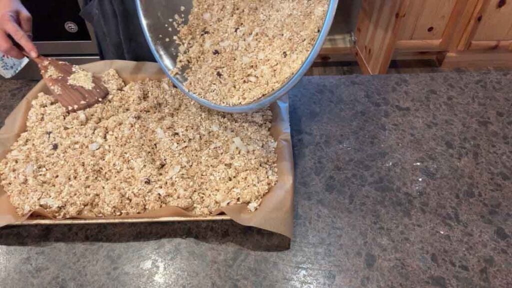 spreading sourdough granola on sheet pans