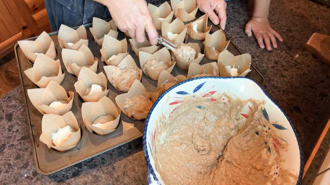 using ice cream scoop to assemble pumpkin muffins