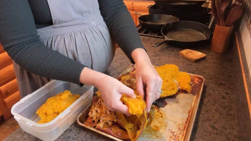 peeling and sorting seeds out of a baked pumpkin for puree-