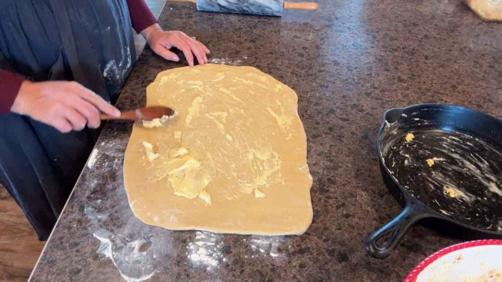 spreading butter on cinnamon rolls