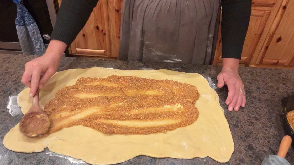 spreading filling on pumpkin cinnamon rolls