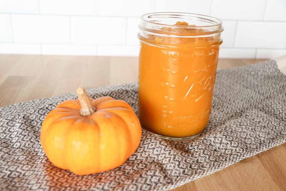jar of pumpkin puree next to a small pumpkin