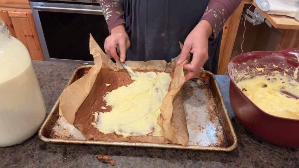 spreading cream cheese on apple cake roll