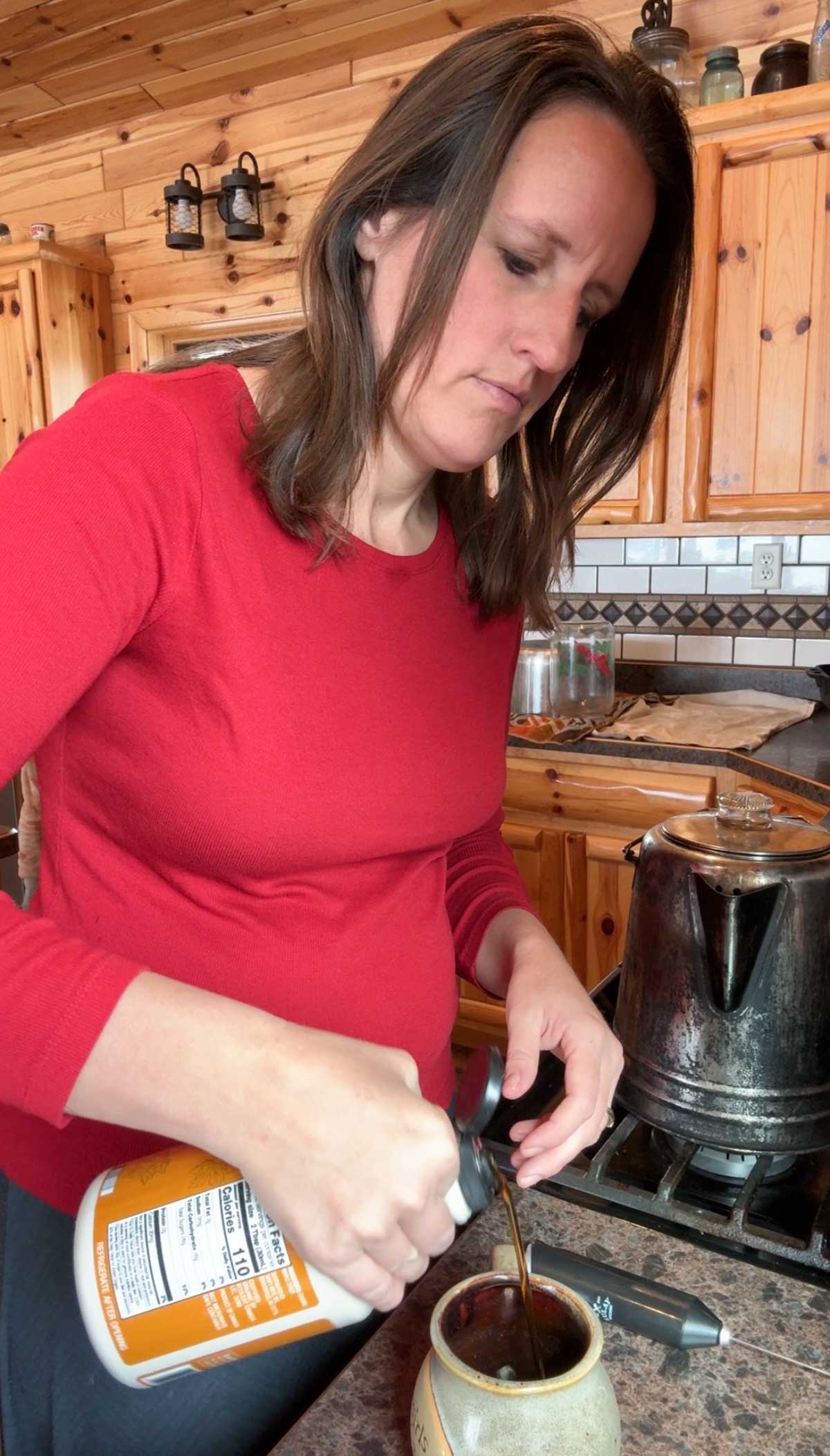 lady adding maple syrup to a coffee cup