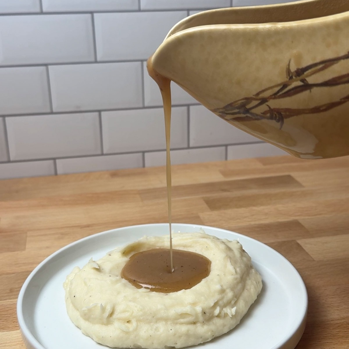 pouring gravy onto mashed potatoes
