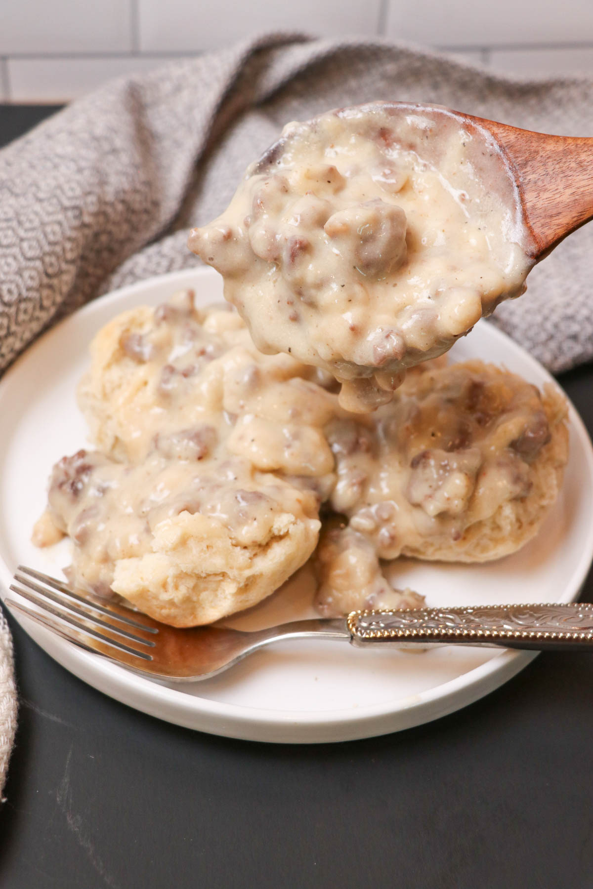 adding sourdough gravy to plate with biscuits
