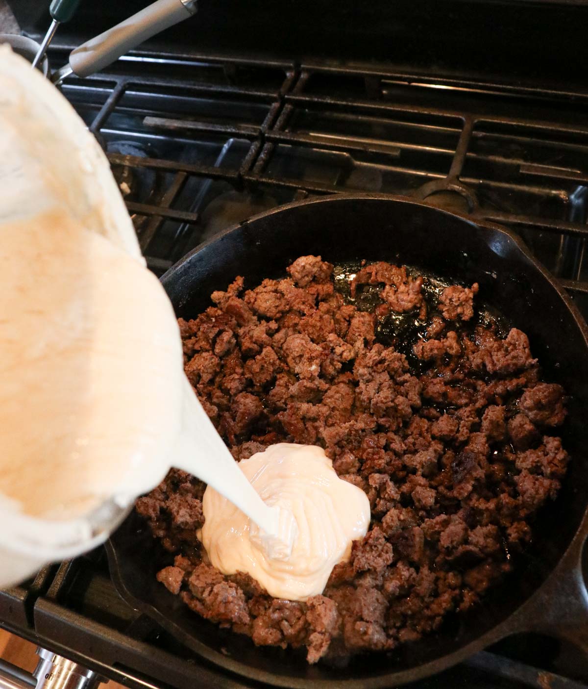 adding sourdough starter to sausage in skillet