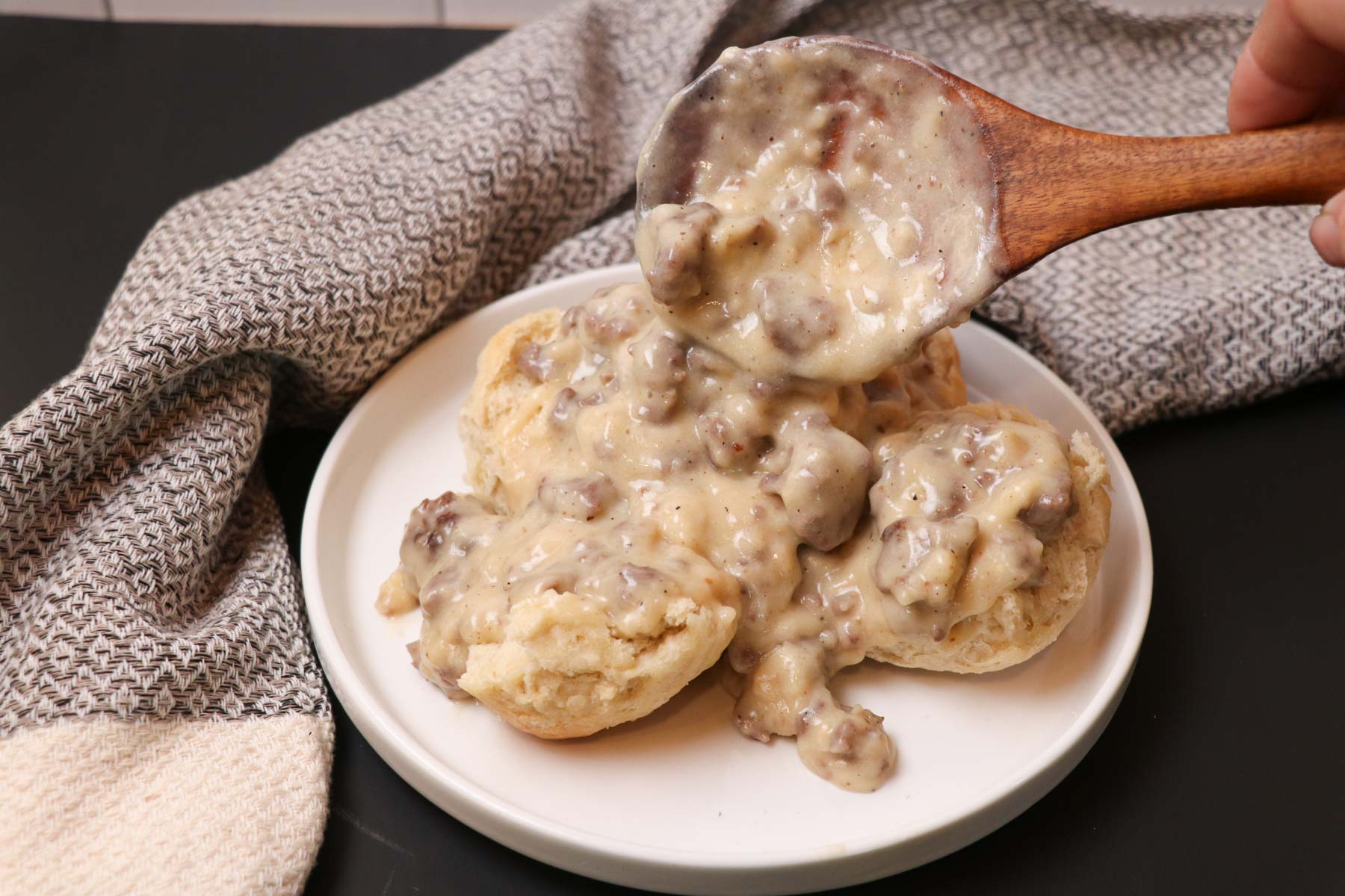 plate of sourdough biscuits and gravy with ladle