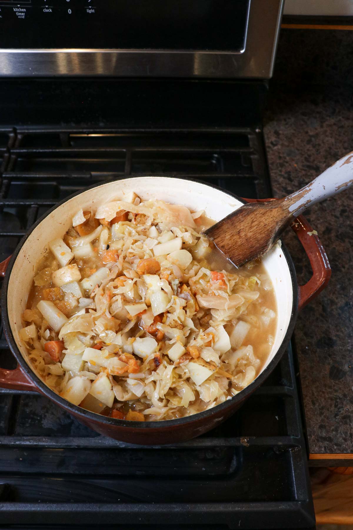 adding broth to sauerkraut sausage soup